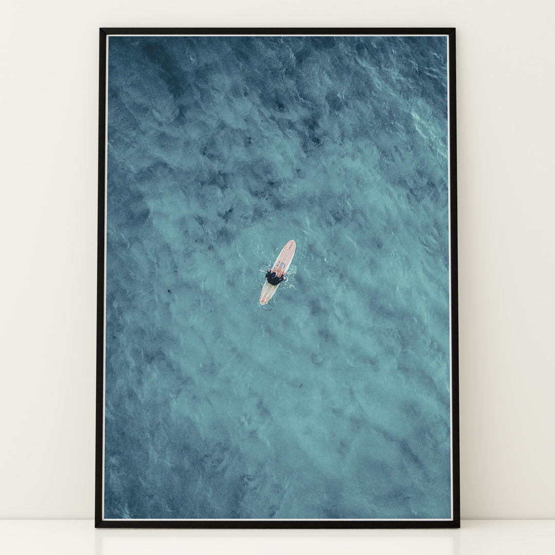 Plakat med surfer på bræt | Sommer og Strand Plakater | Dette luftfoto viser en person på et surfbræt midt i et stort, bølgende blåt-grønt hav. Perfekt til strand- og vandeventyrere.