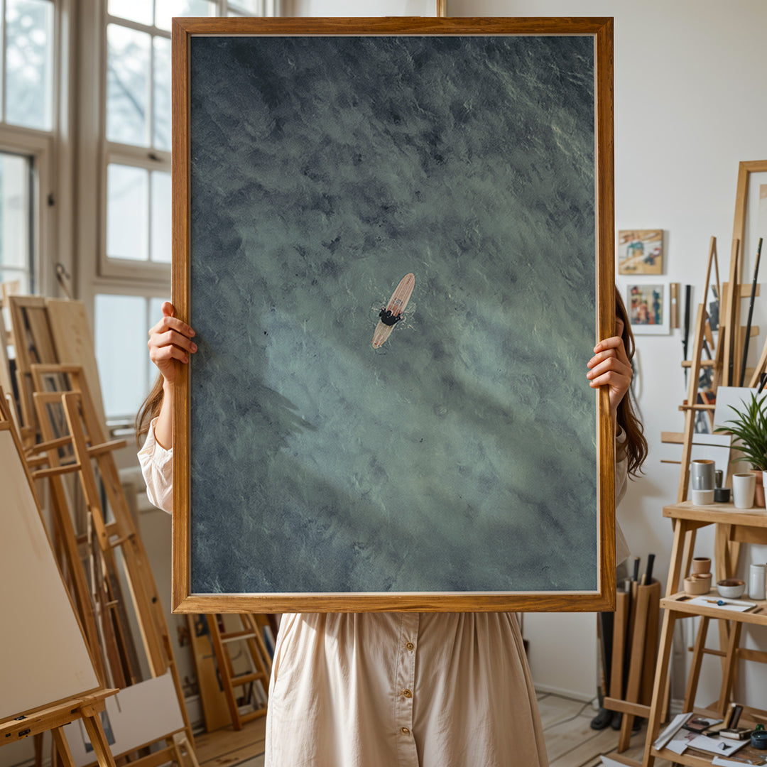 Plakat med surfer på bræt | Sommer og Strand Plakater | Dette luftfoto viser en person på et surfbræt midt i et stort, bølgende blåt-grønt hav. Perfekt til strand- og vandeventyrere.