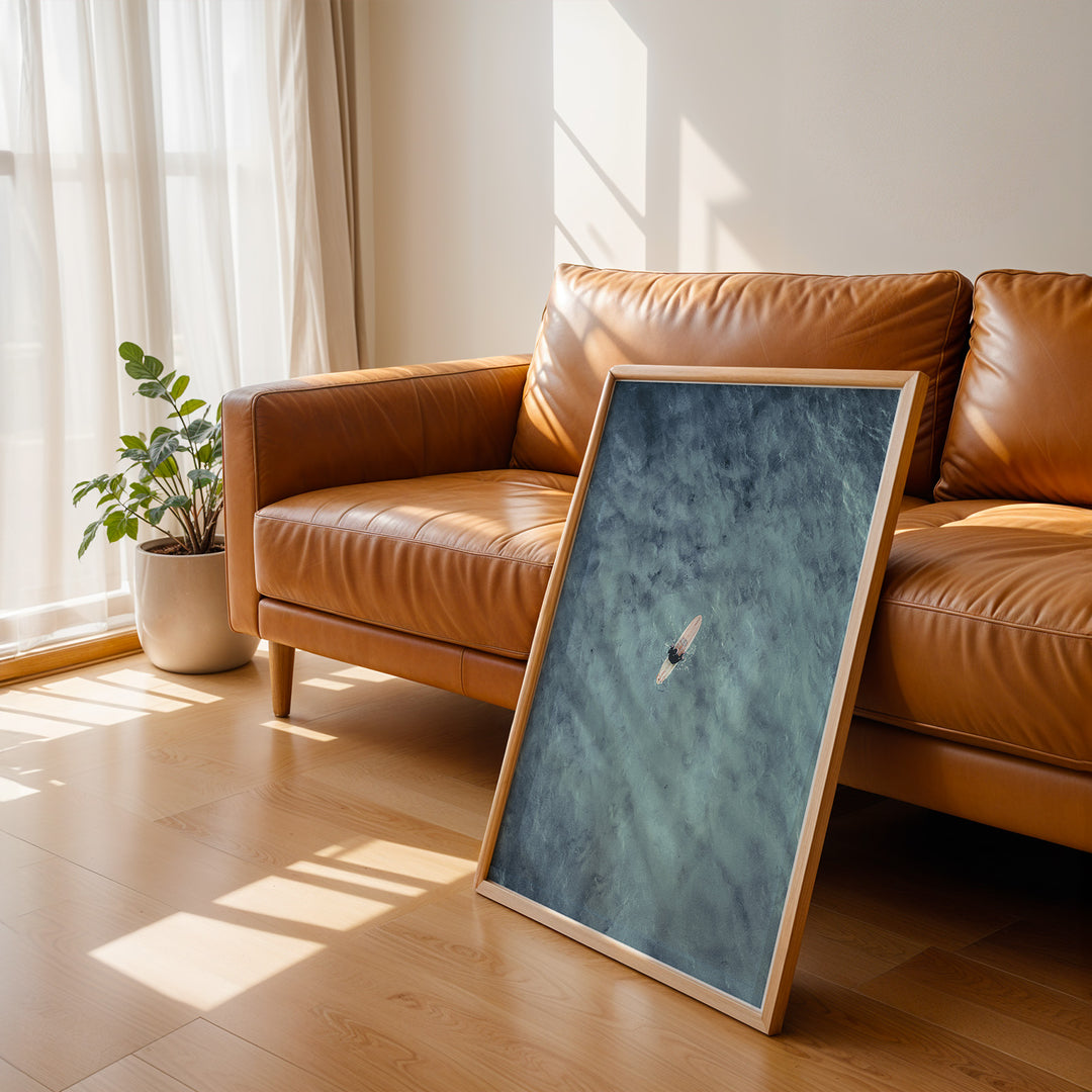 Plakat med surfer på bræt | Sommer og Strand Plakater | Dette luftfoto viser en person på et surfbræt midt i et stort, bølgende blåt-grønt hav. Perfekt til strand- og vandeventyrere.