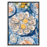 Indlæs billede til gallerivisning Oyster platter art print plakat showing oysters and lemon slices on a blue patterned table with seafood dishes and glassware in a black frame.
