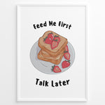 Indlæs billede til gallerivisning Funny kitchen poster with a plate of toast and strawberries, and the text “Feed Me First Talk Later,” framed in black on a white background.
