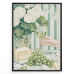 Indlæs billede til gallerivisning Elegant art print plakat of white wine glass, grapes, cheese, and hydrangeas on a green striped table with a hand holding a wine glass in a black frame.
