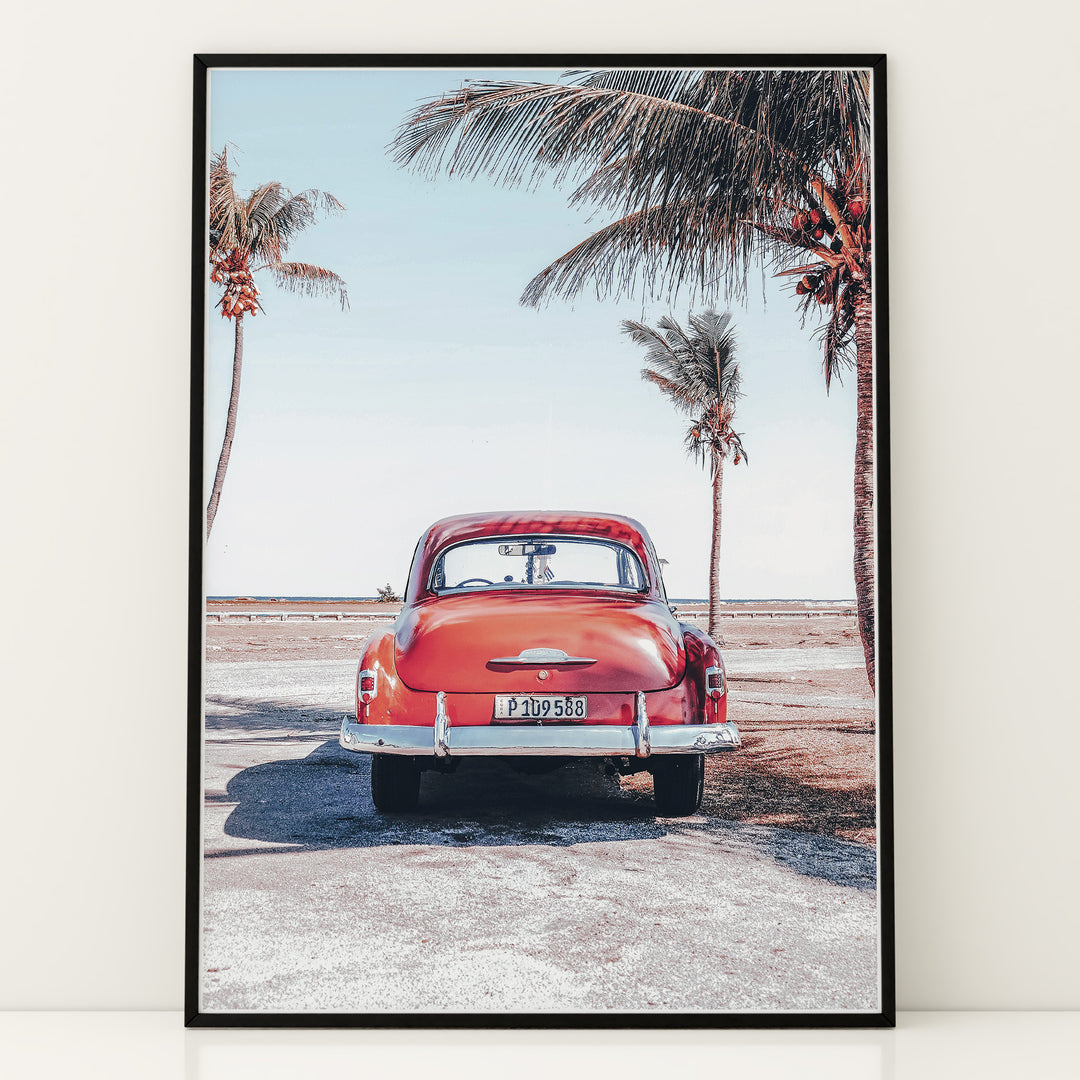 Plakat med vintage bil | Sommer og Strand Plakater | Denne plakat viser en vintage rød bil parkeret ved en strandvej med havet og palmetræer i baggrunden. Perfekt til dem, der elsker retro og strandstemning.