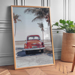 Indlæs billede til gallerivisning Plakat med vintage bil | Sommer og Strand Plakater | Denne plakat viser en vintage rød bil parkeret ved en strandvej med havet og palmetræer i baggrunden. Perfekt til dem, der elsker retro og strandstemning.
