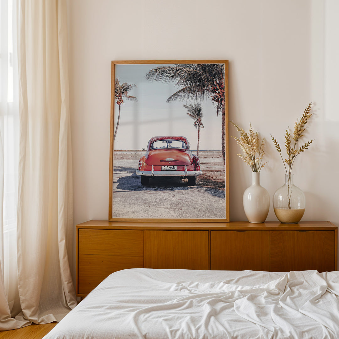 Plakat med vintage bil | Sommer og Strand Plakater | Denne plakat viser en vintage rød bil parkeret ved en strandvej med havet og palmetræer i baggrunden. Perfekt til dem, der elsker retro og strandstemning.