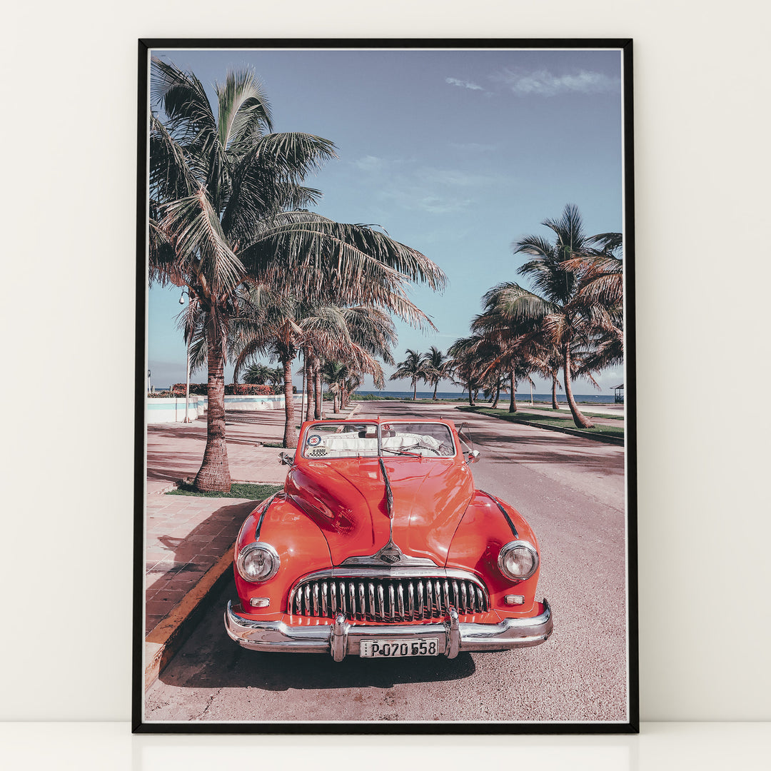 Plakat med vintage rød bil | Sommer og Strand Plakater | Denne plakat viser en klassisk rød cabriolet parkeret på en gade med palmer ved stranden. Perfekt til retro- og strandelskere.