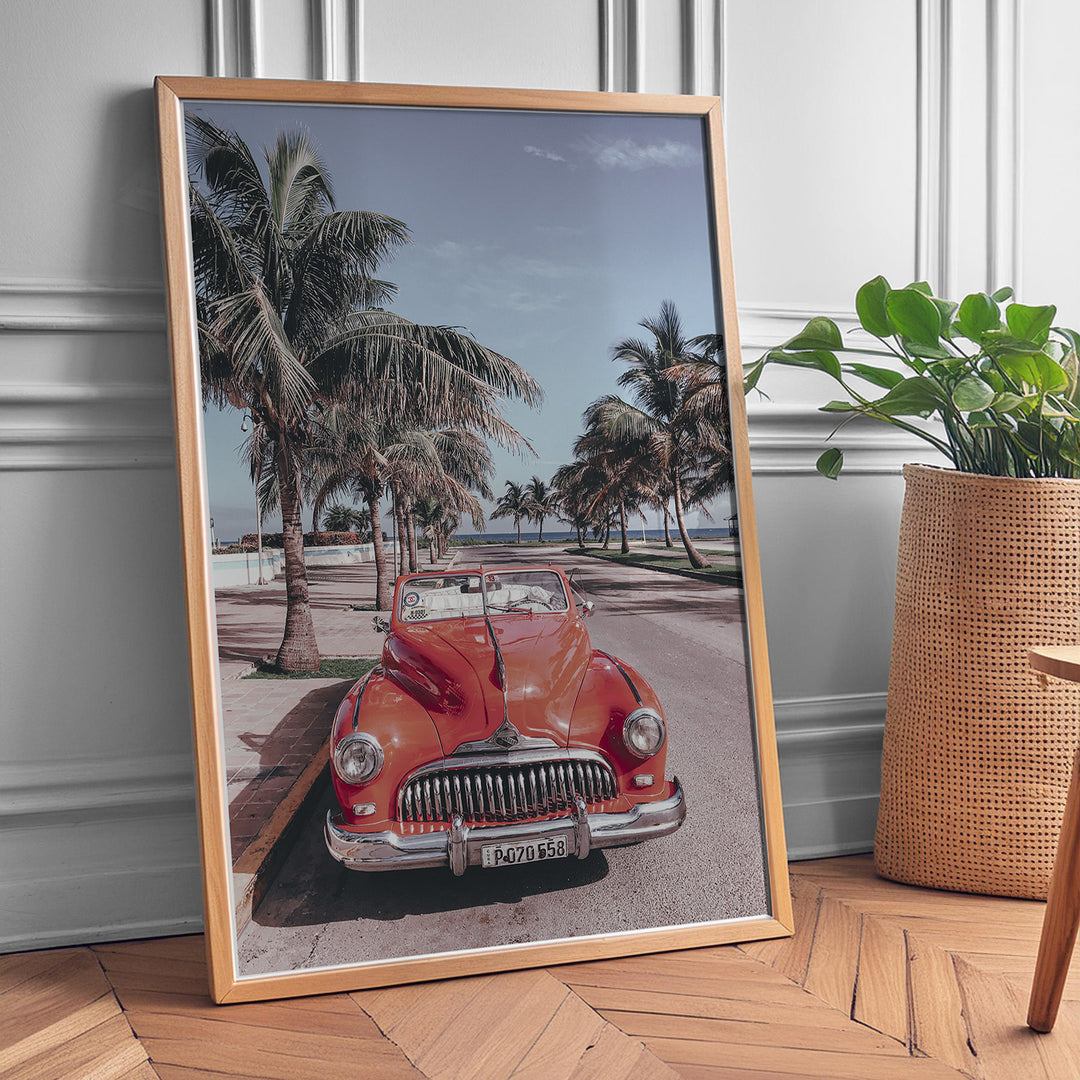 Plakat med vintage rød bil | Sommer og Strand Plakater | Denne plakat viser en klassisk rød cabriolet parkeret på en gade med palmer ved stranden. Perfekt til retro- og strandelskere.