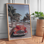 Indlæs billede til gallerivisning Plakat med vintage rød bil | Sommer og Strand Plakater | Denne plakat viser en klassisk rød cabriolet parkeret på en gade med palmer ved stranden. Perfekt til retro- og strandelskere.
