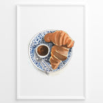 Indlæs billede til gallerivisning Watercolor wall art of a croissant and espresso cup on a blue decorative plate, ideal for French café, kitchen, or breakfast nook wall décor.
