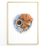 Indlæs billede til gallerivisning Watercolor wall art of a croissant and espresso cup on a blue decorative plate, ideal for French café, kitchen, or breakfast nook wall décor.
