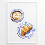 Indlæs billede til gallerivisning Art print of a cappuccino and croissant on blue patterned plates — French café-style kitchen wall décor.
