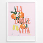 Indlæs billede til gallerivisning Stylish La Dolce Vita poster with oranges, green leaves, and champagne glasses on a pink background, framed as Italian-inspired wall art.

