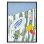 Indlæs billede til gallerivisning Mediterranean still life poster with fish on a white plate, lemon, radishes, olives, and a pink drink on a green and white striped tablecloth, framed as kitchen wall art.
