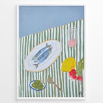 Indlæs billede til gallerivisning Mediterranean still life poster with fish on a white plate, lemon, radishes, olives, and a pink drink on a green and white striped tablecloth, framed as kitchen wall art.
