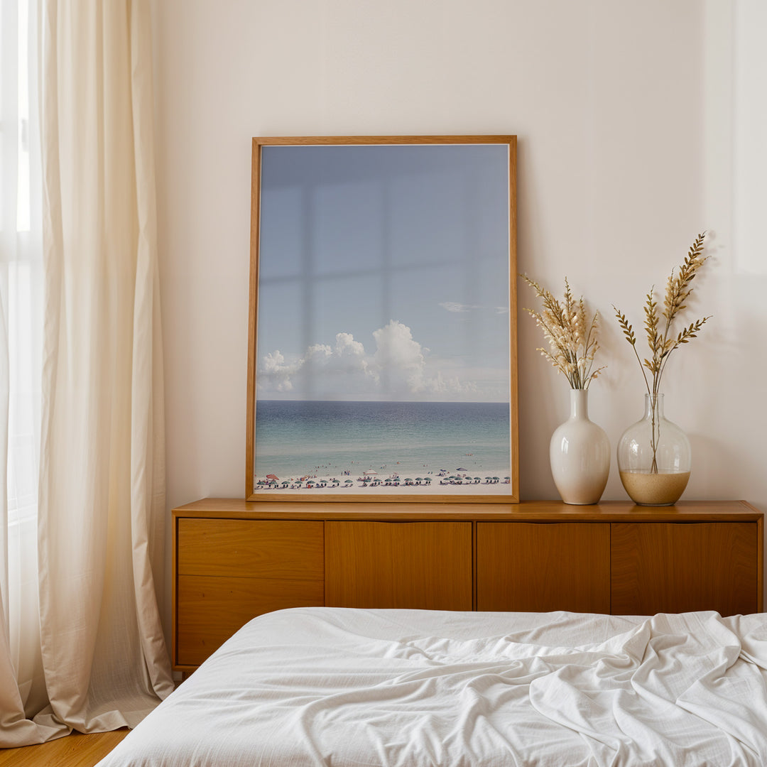 Plakat med strandparadis | Sommer og Strand Plakater | Denne plakat viser en smuk strandscene med et klart blåt hav, farverige parasoller og mennesker, der nyder solen og vandet. Perfekt til dem, der elsker strandliv og afslapning.