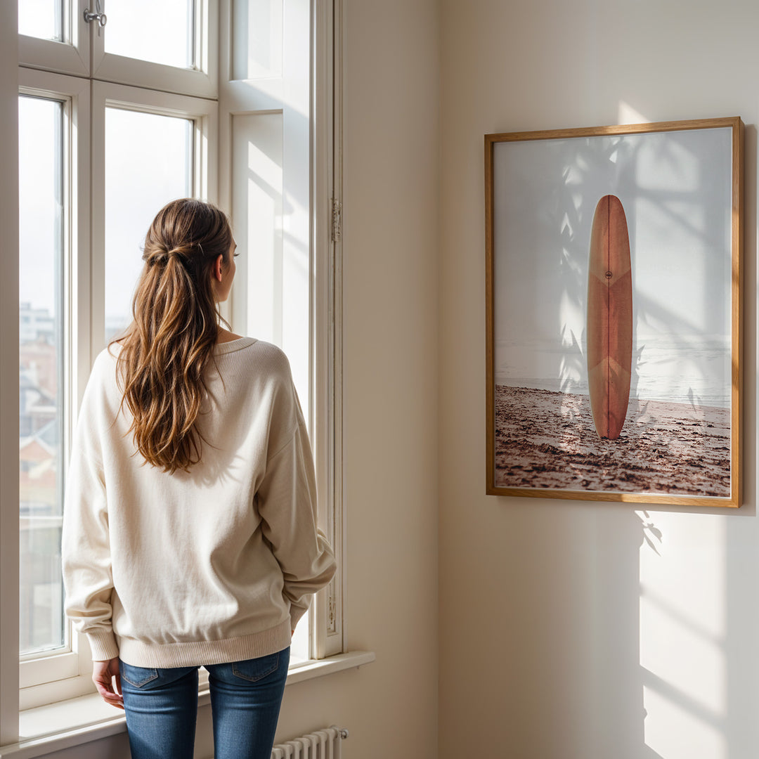 Plakat med surfbræt på stranden | Sommer og Strand Plakater | Denne plakat viser et surfbræt stående oprejst på en rolig sandstrand med havet i baggrunden. Perfekt til strand- og surfentusiaster.