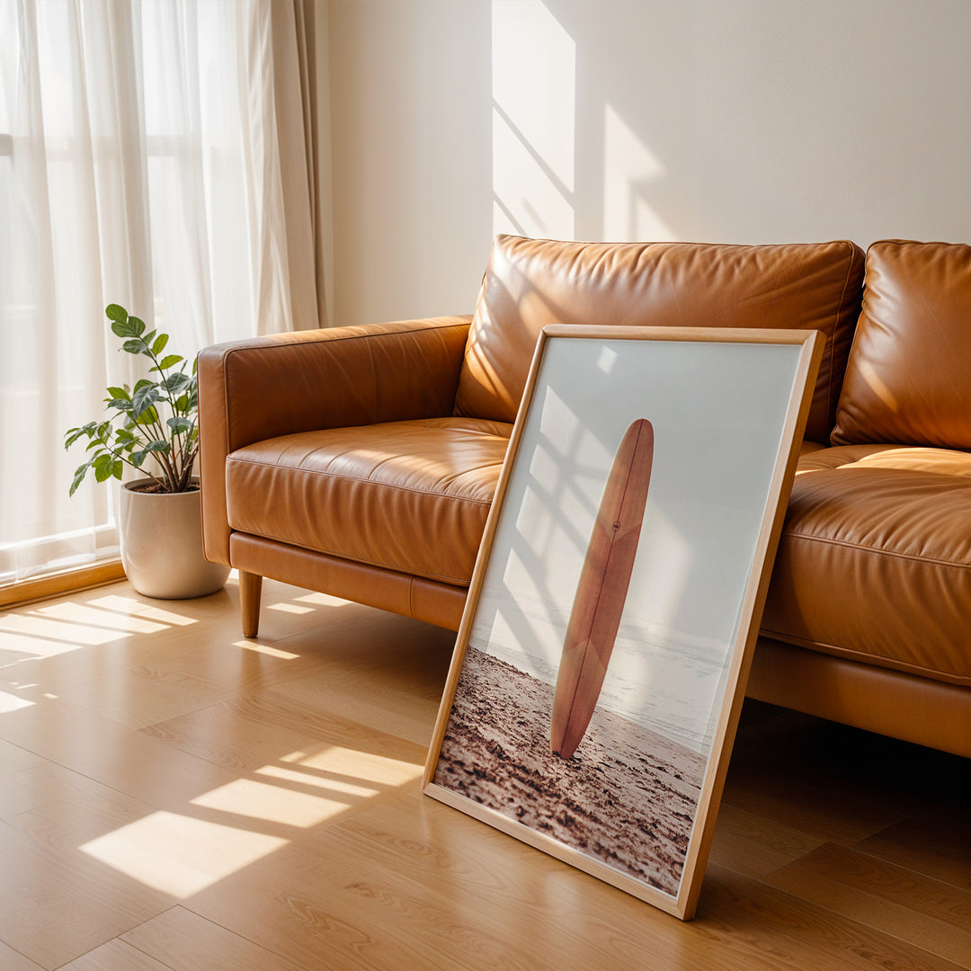 Plakat med surfbræt på stranden | Sommer og Strand Plakater | Denne plakat viser et surfbræt stående oprejst på en rolig sandstrand med havet i baggrunden. Perfekt til strand- og surfentusiaster.