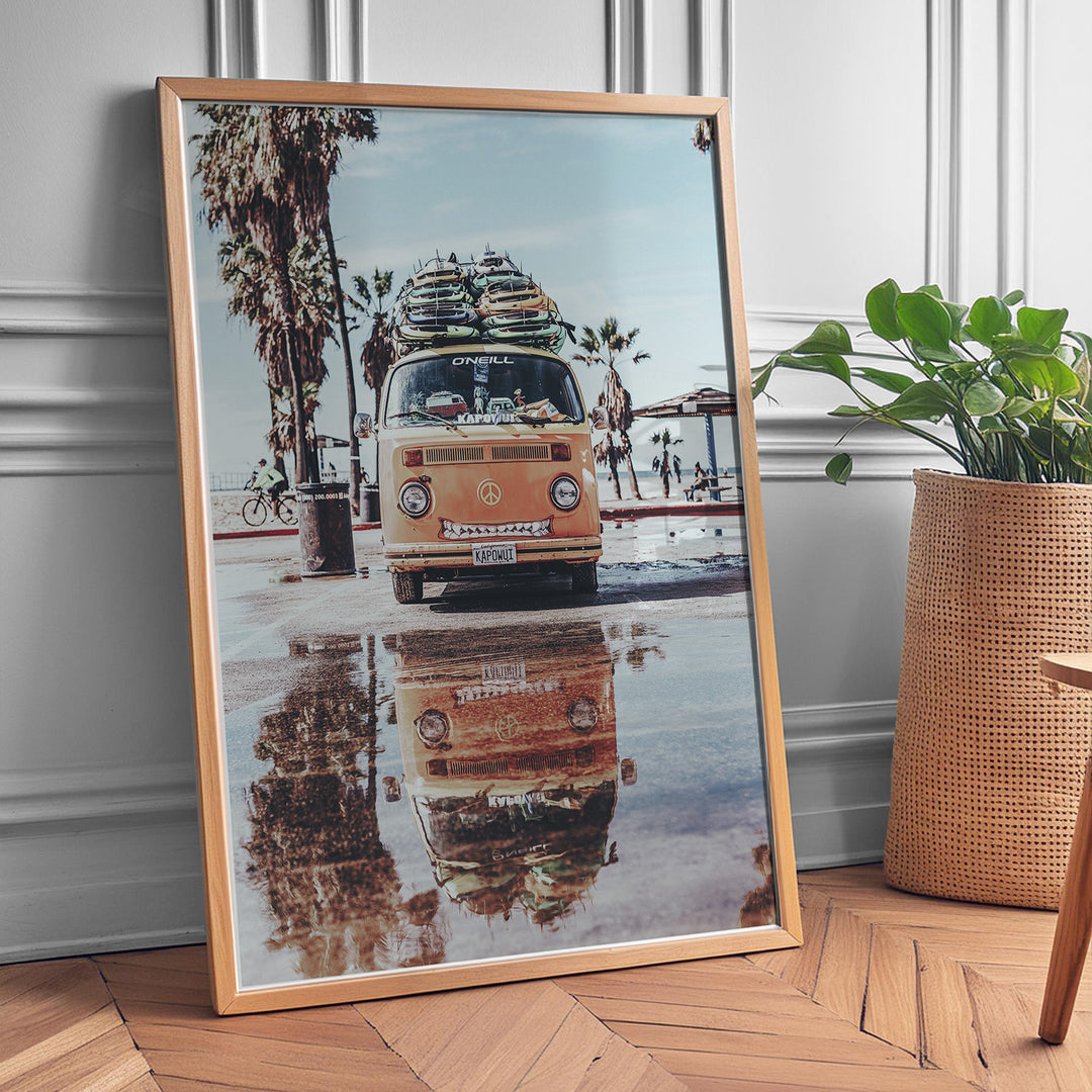 Plakat med Volkswagen surf van | Sommer og Strand Plakater | Denne plakat viser en orange Volkswagen van med surfbrætter på taget, parkeret på en våd overflade med refleksion af vanen i vandet. Perfekt til eventyrlystne sjæle og strandelskere.