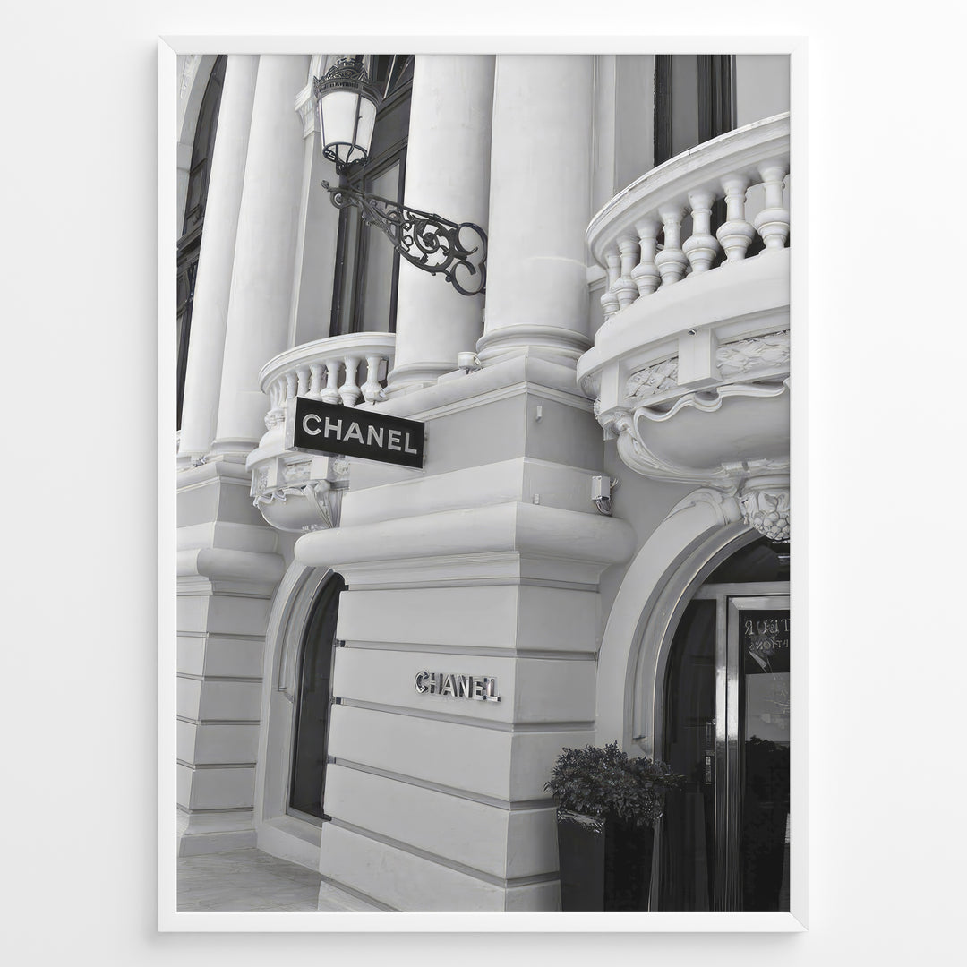 Fashion Plakat | Chanel Boutique Exterior – Monte Carlo, Monaco Plakaty.dk | Black and white photo of the Chanel storefront in Monte Carlo, Monaco, showcasing ornate architecture with columns, balconies, and a hanging sign.