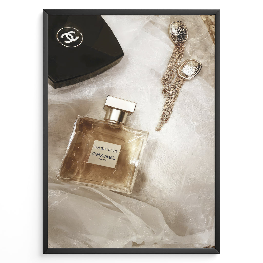 Fashion Plakat | Chanel Gabrielle Perfume Flat Lay with Earrings and Compact – Luxury Beauty Print Plakaty.dk | Flat lay image of Chanel Gabrielle perfume, a black Chanel compact, and gold statement earrings on soft white fabric.