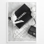 Indlæs billede til gallerivisning Fashion Plakat | Chanel Gift Box &amp; Handbag Flatlay Wall Art Plakaty.dk | Black and white flatlay of a Chanel gift box with ribbon, camellia flowers, and a quilted Chanel handbag on a soft surface.
