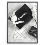 Indlæs billede til gallerivisning Fashion Plakat | Chanel Gift Box &amp; Handbag Flatlay Wall Art Plakaty.dk | Black and white flatlay of a Chanel gift box with ribbon, camellia flowers, and a quilted Chanel handbag on a soft surface.
