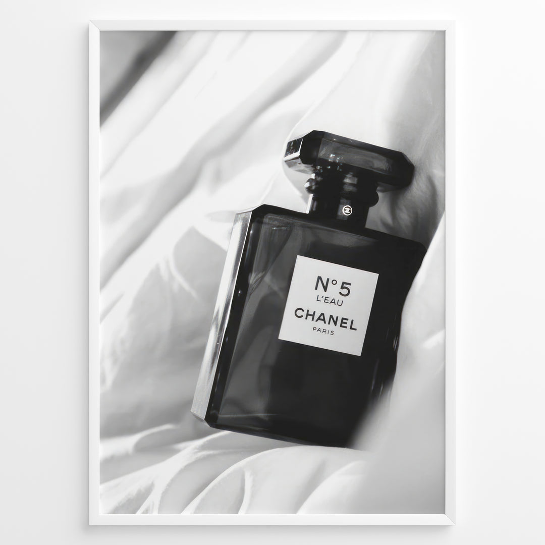 Fashion Plakat | Chanel No. 5 L’Eau Perfume Bottle – Black and White Fashion Photography Plakaty.dk | Black and white photo of a Chanel No. 5 L’Eau perfume bottle resting on a bed of soft white fabric.