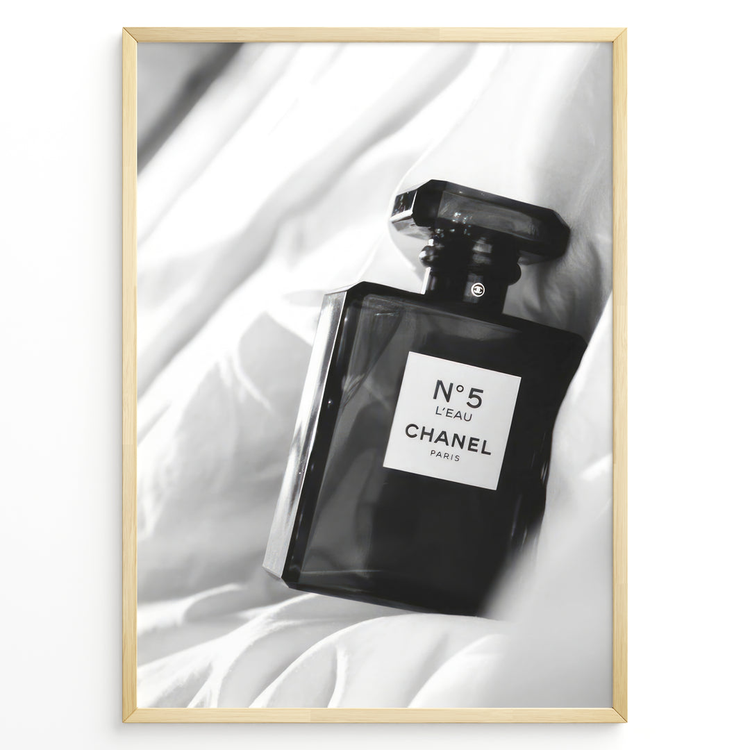 Fashion Plakat | Chanel No. 5 L’Eau Perfume Bottle – Black and White Fashion Photography Plakaty.dk | Black and white photo of a Chanel No. 5 L’Eau perfume bottle resting on a bed of soft white fabric.
