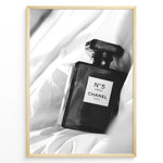Indlæs billede til gallerivisning Fashion Plakat | Chanel No. 5 L’Eau Perfume Bottle – Black and White Fashion Photography Plakaty.dk | Black and white photo of a Chanel No. 5 L’Eau perfume bottle resting on a bed of soft white fabric.
