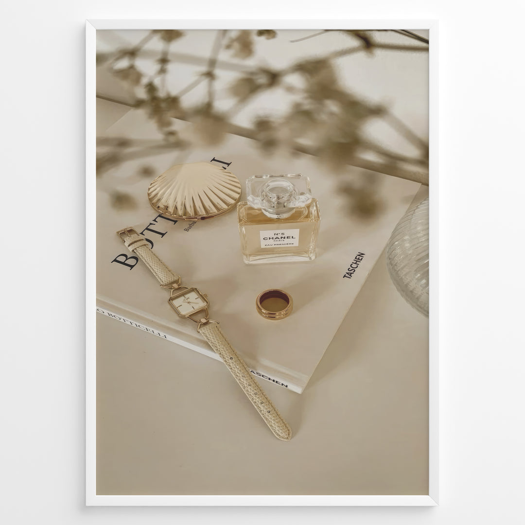 Fashion Plakat | Chanel No. 5 Perfume Flat Lay with Watch and Books – Neutral Aesthetic Print Plakaty.dk | Flat lay of Chanel No. 5 perfume bottle, gold watch, ring, and decorative shell on fashion books with soft floral blur in neutral tones.