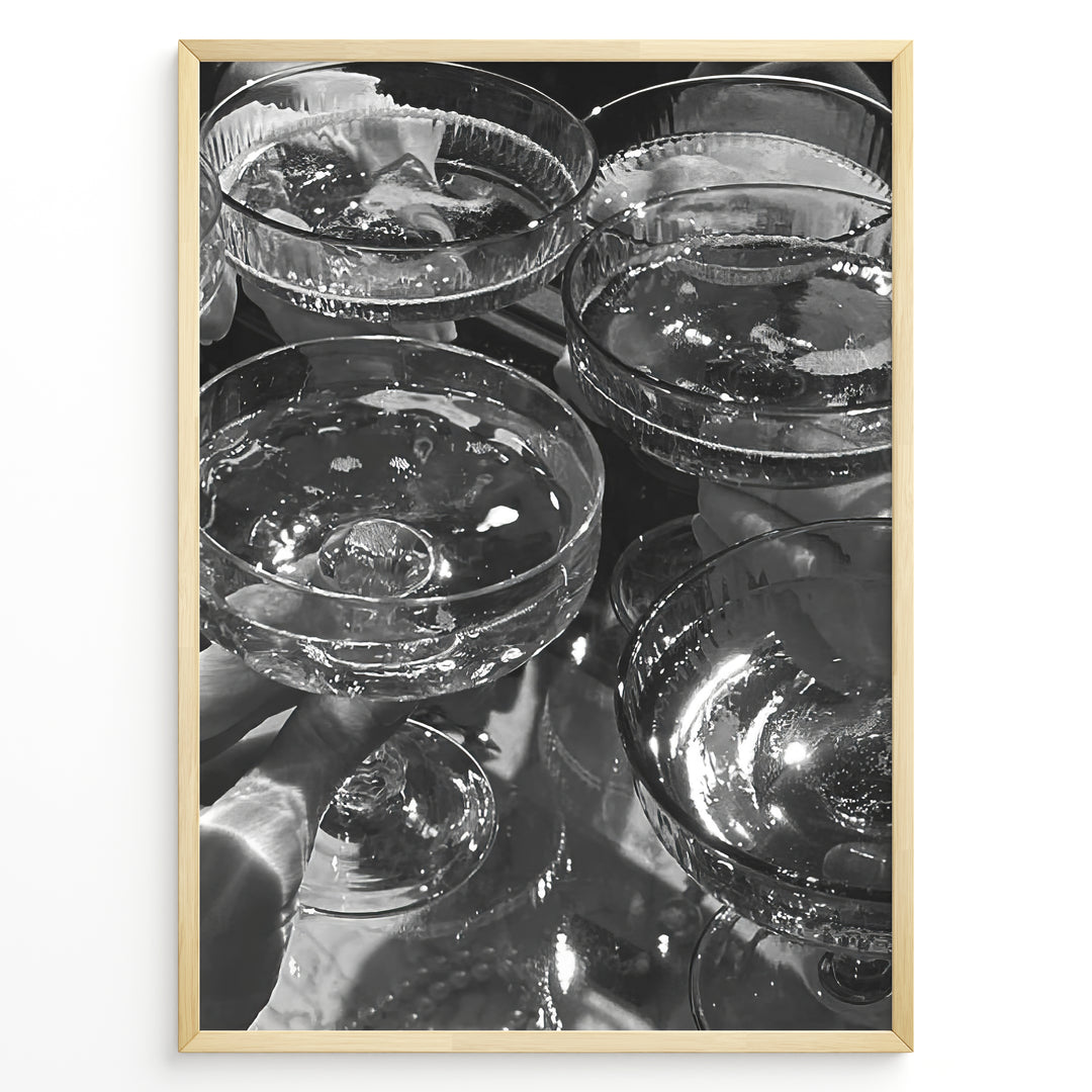Fashion Plakat | Cheers in Black & White: Luxe Champagne Coupes Wall Art Plakaty.dk | Black and white photo of multiple champagne coupe glasses being raised in a celebratory toast, reflecting light and bubbles.