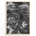 Indlæs billede til gallerivisning Fashion Plakat | Cheers in Black &amp; White: Luxe Champagne Coupes Wall Art Plakaty.dk | Black and white photo of multiple champagne coupe glasses being raised in a celebratory toast, reflecting light and bubbles.
