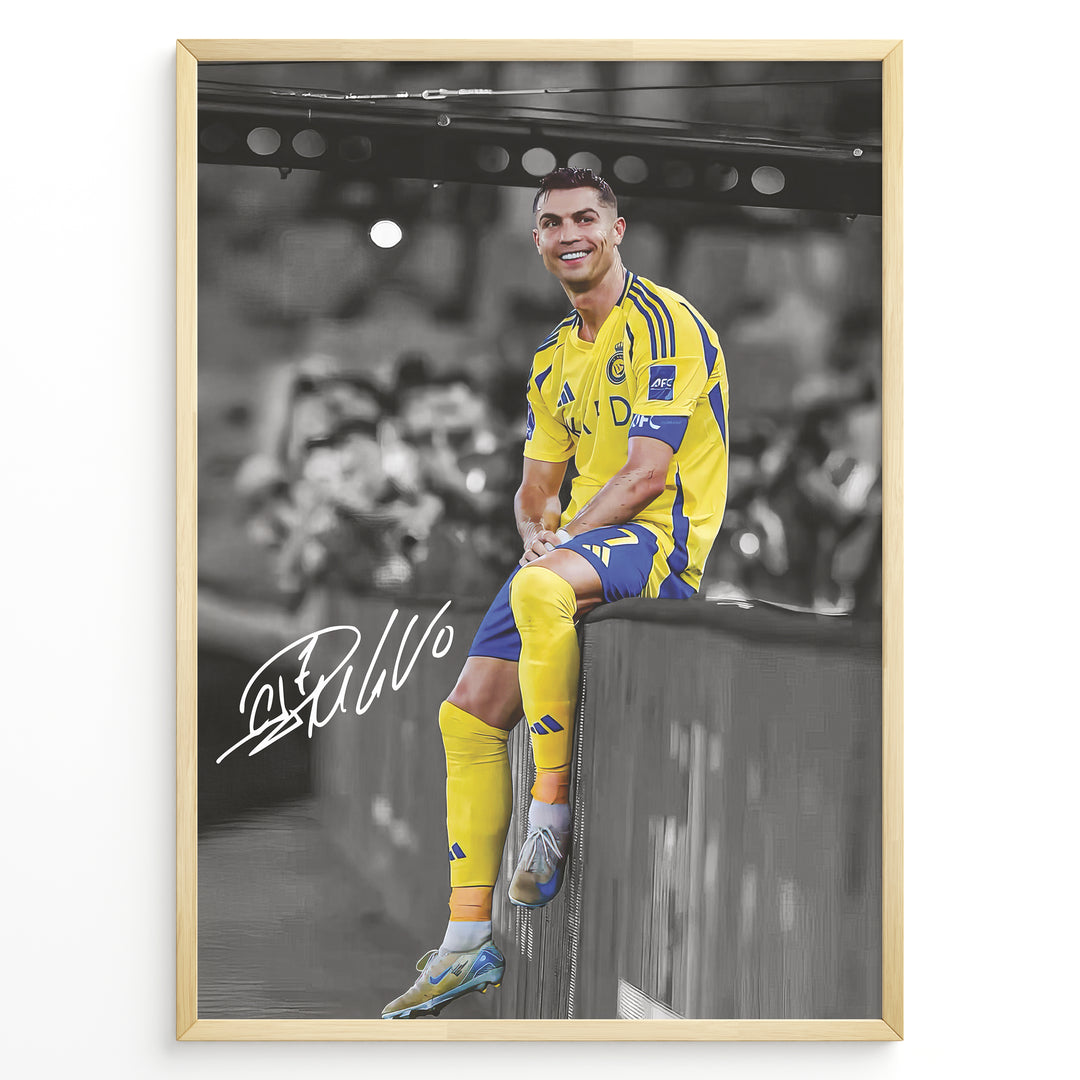 Cristiano Ronaldo sitting on barrier wearing Al Nassr yellow jersey framed plakat