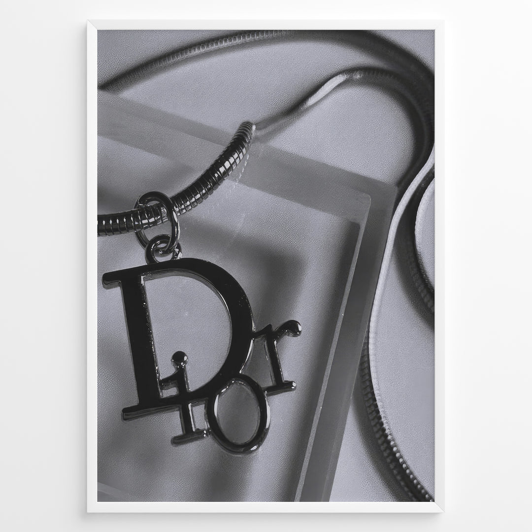 Fashion Plakat | Dior Pendant Necklace – Elegant Black & White Fashion Print Plakaty.dk | Black and white close-up image of a Dior pendant necklace with a metallic chain, showcasing luxury jewelry on a textured background.