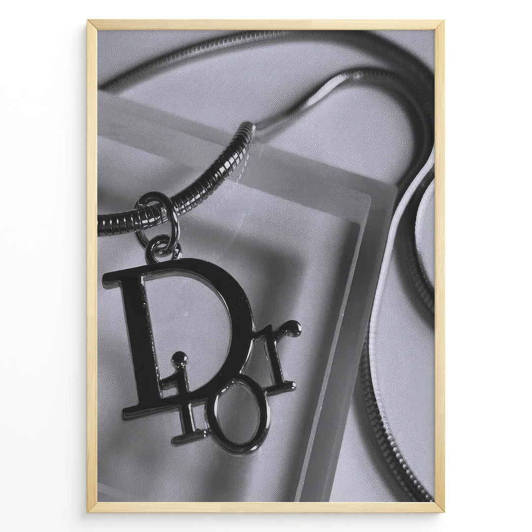 Fashion Plakat | Dior Pendant Necklace – Elegant Black & White Fashion Print Plakaty.dk | Black and white close-up image of a Dior pendant necklace with a metallic chain, showcasing luxury jewelry on a textured background.