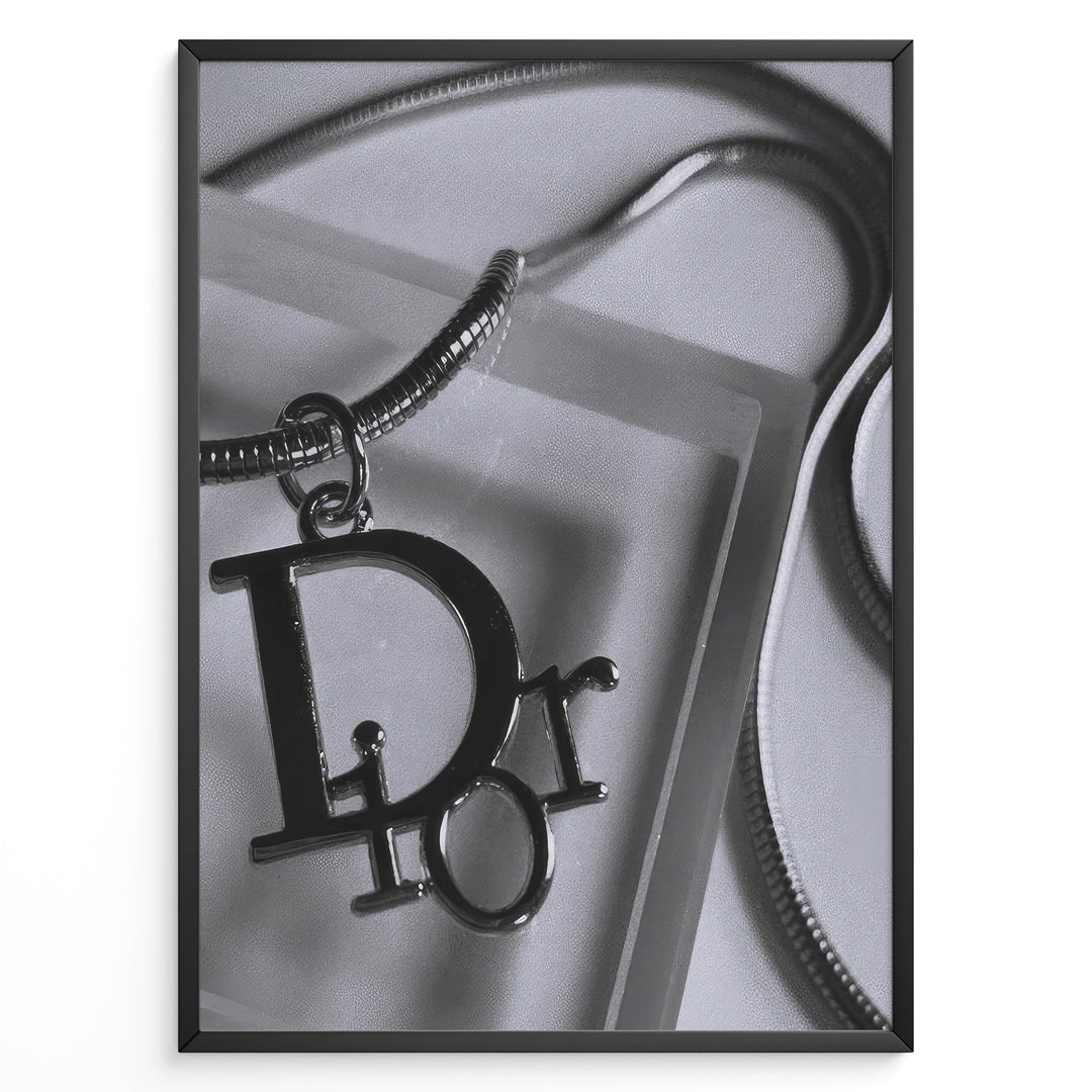 Fashion Plakat | Dior Pendant Necklace – Elegant Black & White Fashion Print Plakaty.dk | Black and white close-up image of a Dior pendant necklace with a metallic chain, showcasing luxury jewelry on a textured background.