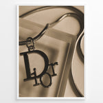 Indlæs billede til gallerivisning Fashion Plakat | Dior Sepia Necklace Charm – Vintage-Inspired Fashion Wall Art Plakaty.dk | Sepia-toned Dior necklace charm with close-up detail on a textured surface, styled as vintage fashion wall art.
