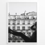 Indlæs billede til gallerivisning Fashion Plakat | Elegant Woman Relaxing on Parisian Balcony – Black and White Photography Plakaty.dk | Black and white photo of a woman relaxing on a Parisian balcony with classic building architecture in the background
