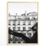 Indlæs billede til gallerivisning Fashion Plakat | Elegant Woman Relaxing on Parisian Balcony – Black and White Photography Plakaty.dk | Black and white photo of a woman relaxing on a Parisian balcony with classic building architecture in the background
