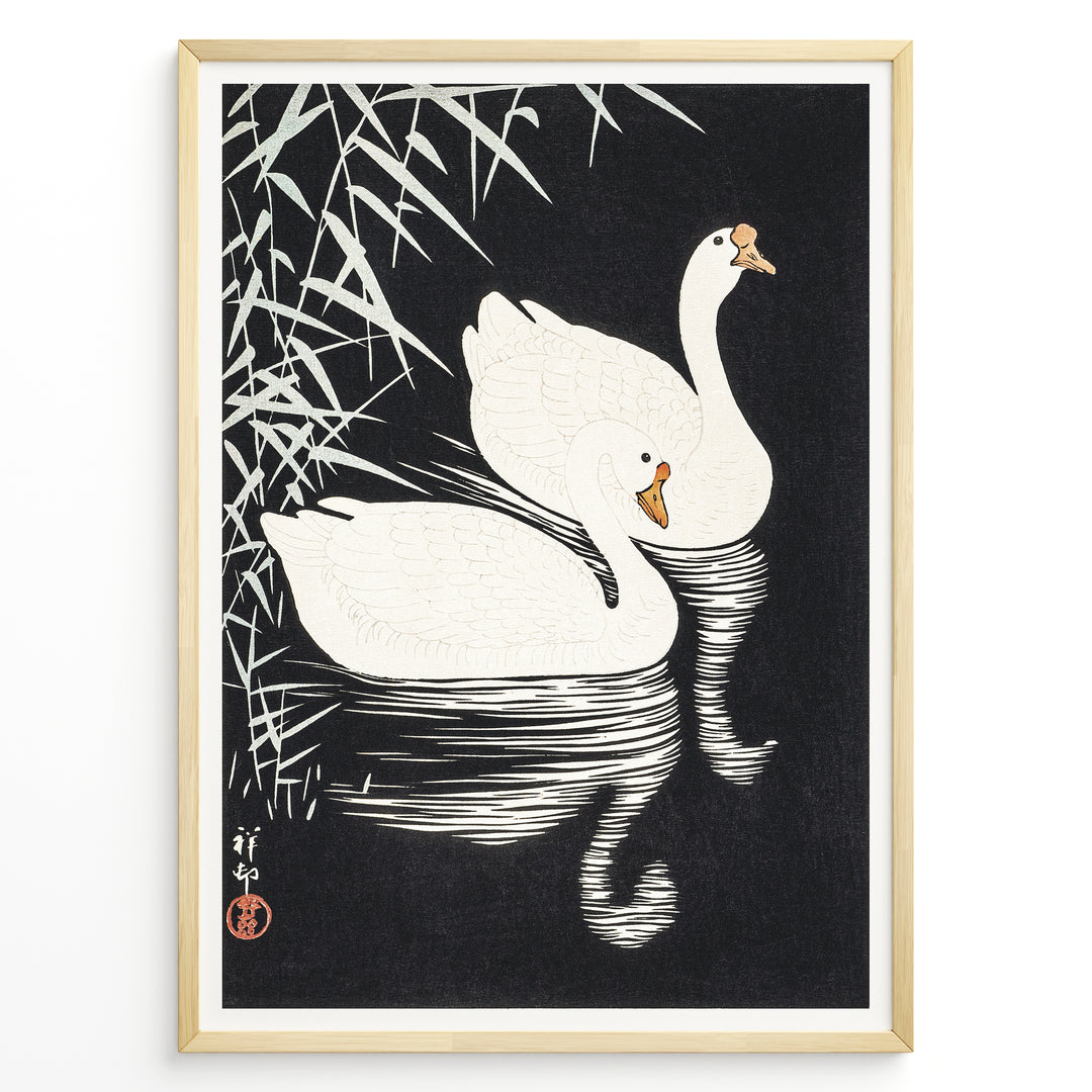 Framed Japanese Ukiyo-e style art poster showing two white swans gliding on dark water with bamboo leaves above.
