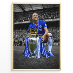 Indlæs billede til gallerivisning John Terry im Chelsea-Trikot mit der Premier-League-Trophäe vor den Chelsea-Fans. Die ikonischen blauen Farben heben sich vom schwarz-weißen Stadionhintergrund ab.
