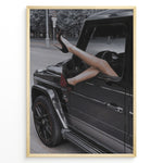 Indlæs billede til gallerivisning Fashion Plakat | Luxury Escape: Legs in High Heels Through Mercedes G-Wagon Window Plakaty.dk | Woman&#39;s legs in high heels sticking out of a Mercedes-Benz G-Wagon window in an urban street scene.
