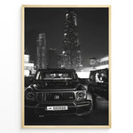Indlæs billede til gallerivisning Fashion Plakat | Midnight Luxury – Brabus G-Wagon in Dubai Plakaty.dk | Black and white photo of a Brabus G-Wagon parked in front of the Dubai skyline at night, with skyscrapers like Burj Khalifa and EMAAR towers in the background.
