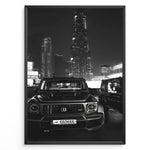 Indlæs billede til gallerivisning Fashion Plakat | Midnight Luxury – Brabus G-Wagon in Dubai Plakaty.dk | Black and white photo of a Brabus G-Wagon parked in front of the Dubai skyline at night, with skyscrapers like Burj Khalifa and EMAAR towers in the background.

