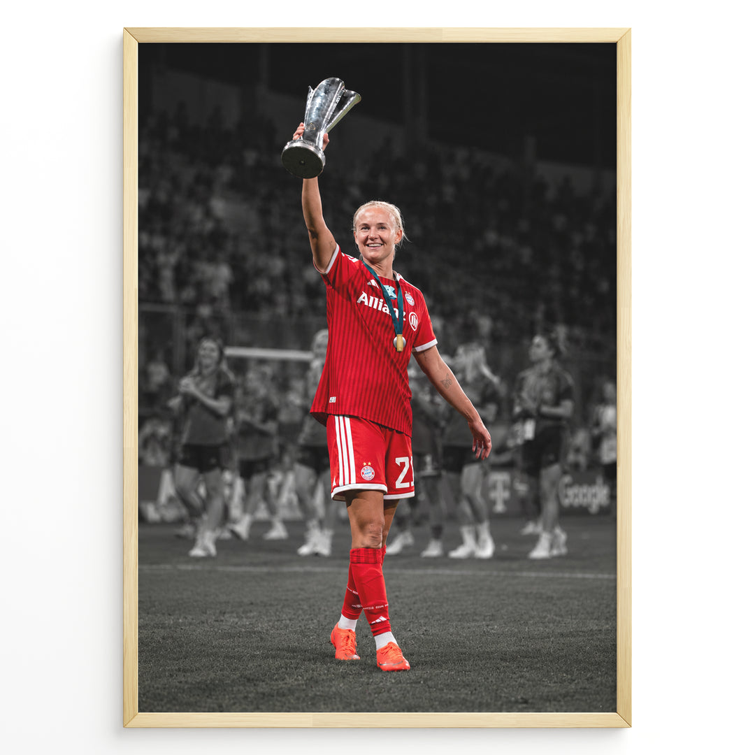 Pernille Harder im Bayern-München-Trikot mit einer Trophäe auf einem stilvollen schwarz-weißen Fußballposter.