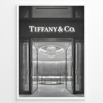 Indlæs billede til gallerivisning Fashion Plakat | Tiffany &amp; Co. Entrance – Luxury Jewelry Store Poster in Black &amp; White Plakaty.dk | Black and white photo of the Tiffany &amp; Co. boutique entrance with glass doors, a chandelier inside, and the illuminated brand name above.

