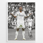 Indlæs billede til gallerivisning Framed Plakat of Vinícius Jr. in a Real Madrid kit doing a shrug celebration, with a black and white background and visible signature
