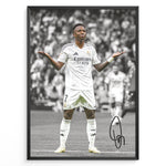 Indlæs billede til gallerivisning Framed Plakat of Vinícius Jr. in a Real Madrid kit doing a shrug celebration, with a black and white background and visible signature
