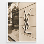 Indlæs billede til gallerivisning Fashion Plakat | Yves Saint Laurent Sepia Storefront – Vintage Luxury Wall Art Plakaty.dk | Sepia-toned photo of the Yves Saint Laurent storefront with a prominent YSL logo on a white wall and reflections of the cityscape in the background.
