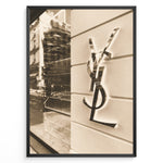 Indlæs billede til gallerivisning Fashion Plakat | Yves Saint Laurent Sepia Storefront – Vintage Luxury Wall Art Plakaty.dk | Sepia-toned photo of the Yves Saint Laurent storefront with a prominent YSL logo on a white wall and reflections of the cityscape in the background.
